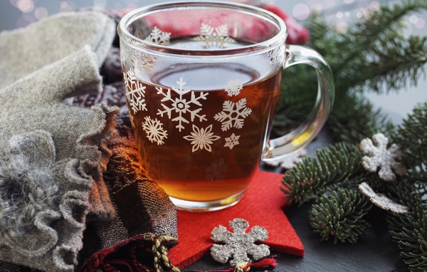Стеклянная чашка чая на столе с ветками ели и шарфом 