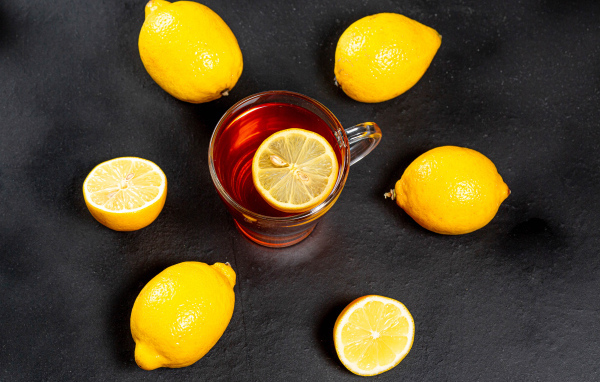 Стеклянная чашка чая с лимоном на сером столе 