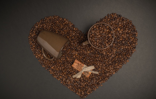 Сердце из кофейных зерен на сером фоне с кружками 