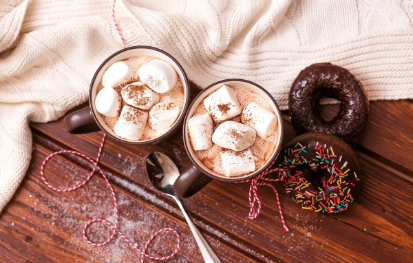 Горячий какао с маршмеллоу с пончиками на столе 