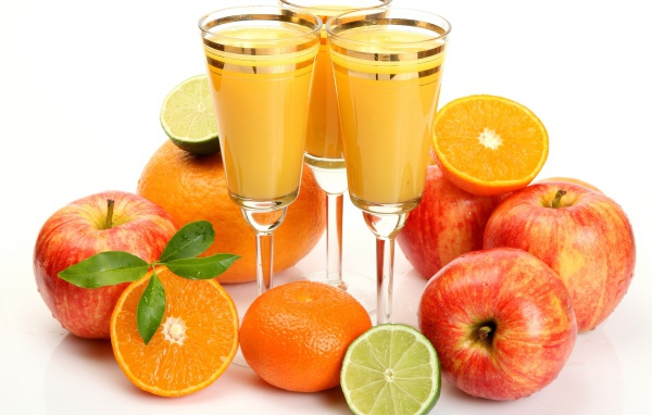 Сок в фужерах на столе с яблоками и мандаринами 
