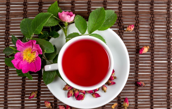 Красный чай с шиповника на столе с цветами