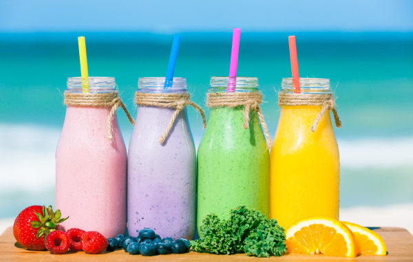Три бутылочки со смузи на столе на пляже