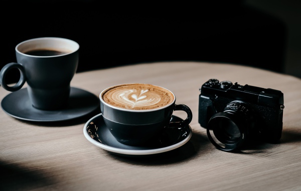 Две чашки кофе на столе с фотоаппаратом 