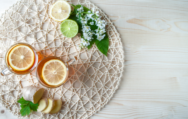 Две чашки чая с лимоном на плетеной подставке 