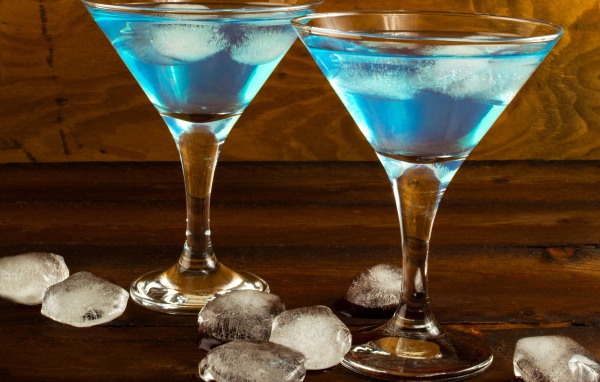 Два бокала коктейля на столе с кусочками льда