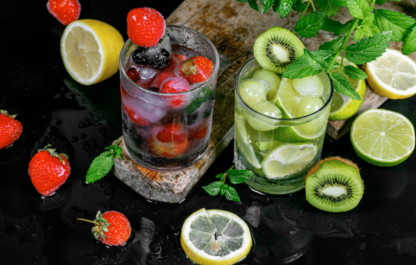 Два стакана мохито на столе с мятой, лимоном и клубникой 