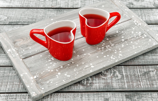 Две красные чашки в форме сердца на столе 