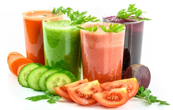 Овощные соки на столе с огурцами, помидорами, морковью и свеклой 