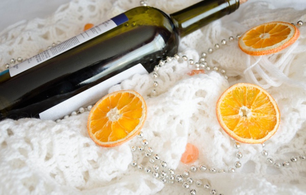 Бутылка вина и кусочки апельсина на белом платке 