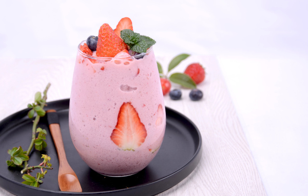 Йогурт в стакане с ягодами черники и клубники