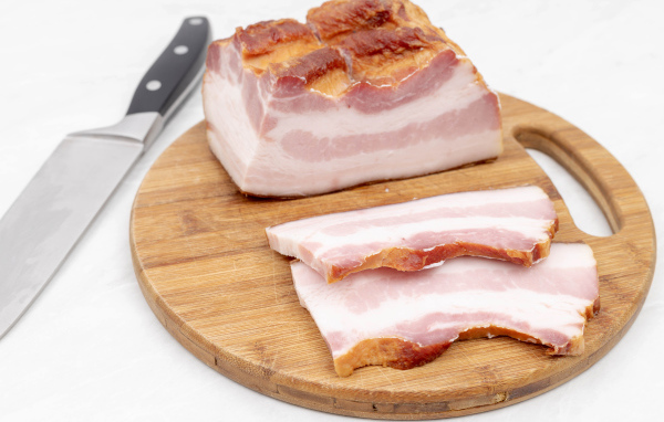 Кусок вкусного копченого сала на доске с ножом