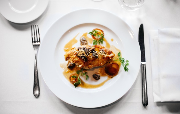 Кусок жареного мяса на большой белой тарелке 