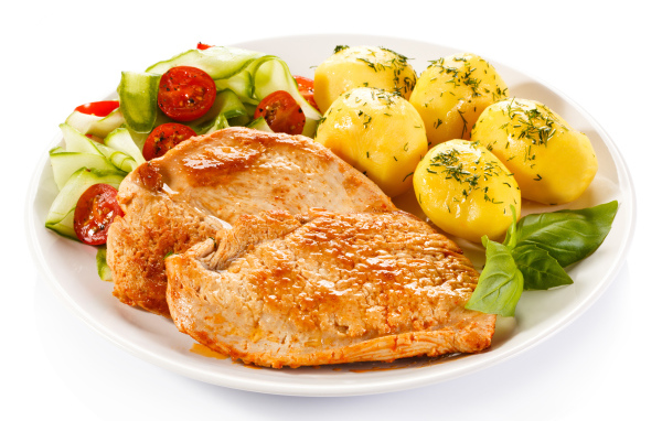 Кусок сочного куриного мяса на тарелке с картофелем и салатом