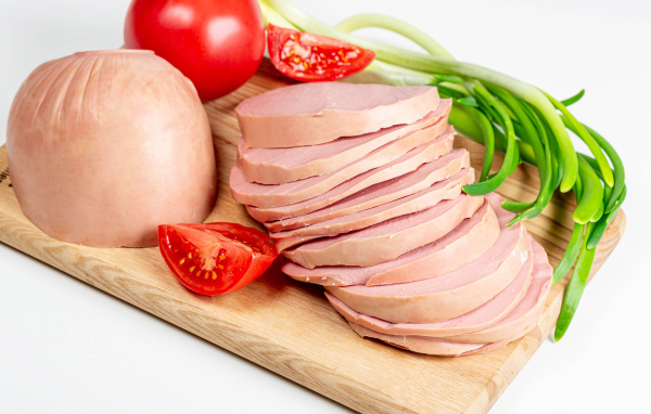 Вареная колбаса на доске с луком и помидором