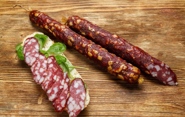 Вкусная сухая колбаса на столе с бутербродом