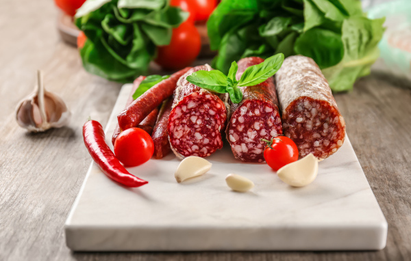 Вкусные колбасные изделия на столе с овощами