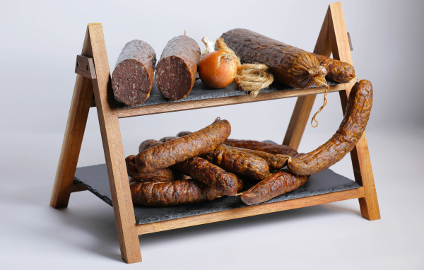 Различные виды колбасы на полке с луком на сером фоне