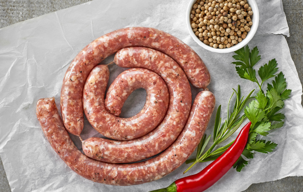 Домашняя колбаса на столе с зеленью и перцем