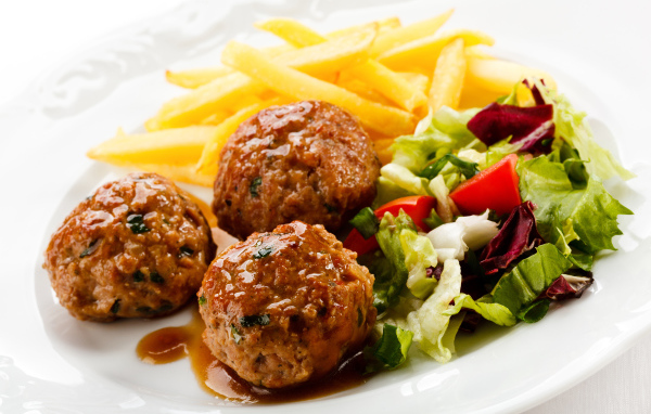 Фрикадельки с салатом и картофелем фри на белой тарелке