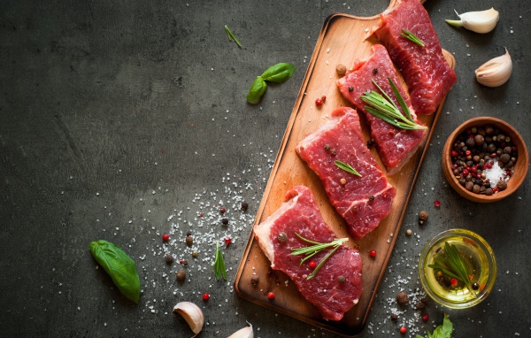 Куски мяса со специями и зеленью на доске 