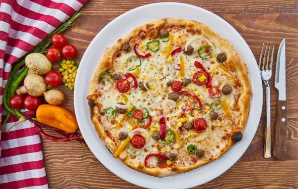 Аппетитная вкусная пицца на столе с овощами 