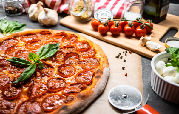 Пицца пепперони на столе с овощами и специями