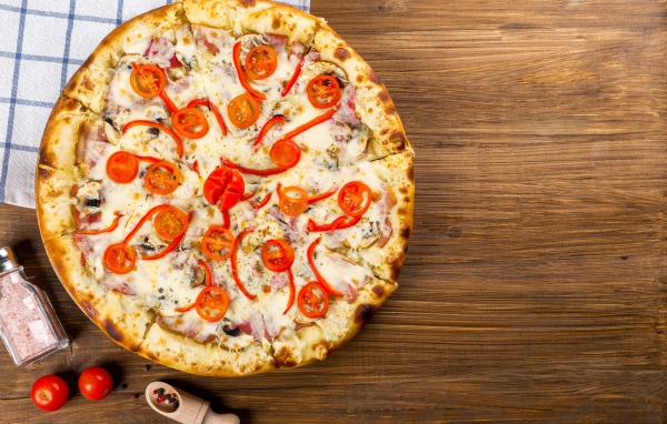 Пицца с беконом на столе с помидорами  и перцем