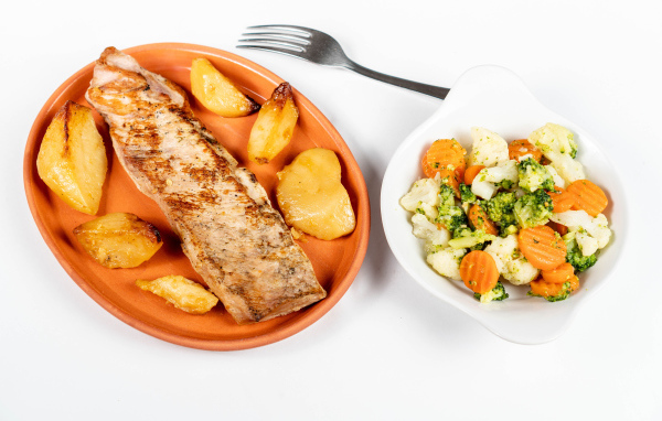 Кусок запеченной рыбы на тарелке с овощами 
