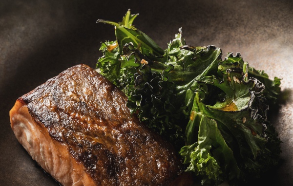 Кусок запеченной рыбы с листьями салата в сковороде 