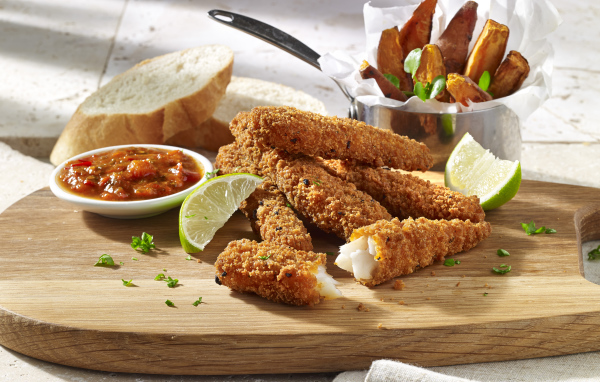 Рыба в панировке на столе с соусом и кусочками лайма