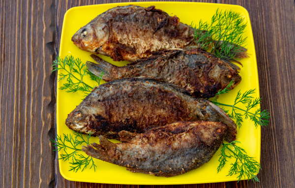 Grilled crucian with dill on a yellow plate