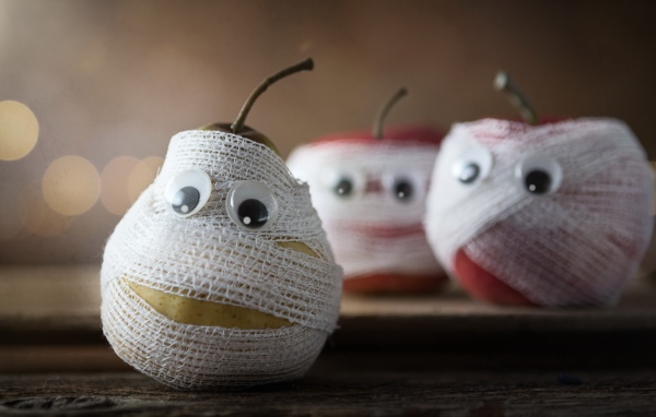 Груши и яблоки в бинтах на столе 