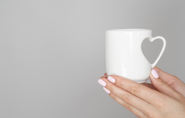 Белая кружка в руках девушки на сером фоне