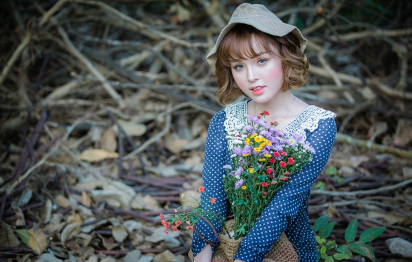 Молодая девушка азиатка с букетом цветов сидит на ветках