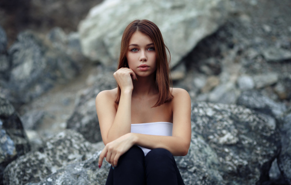 Молодая девушка сидит на камнях 