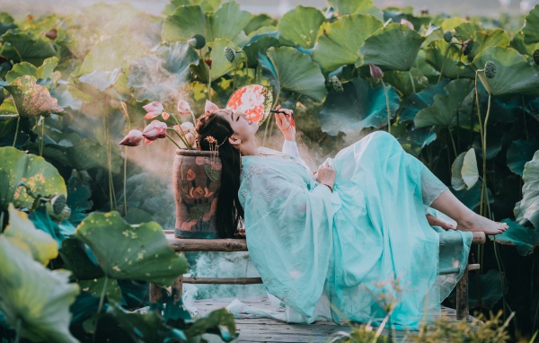 Девушка азиатка в красивом голубом платье на поле лотосов