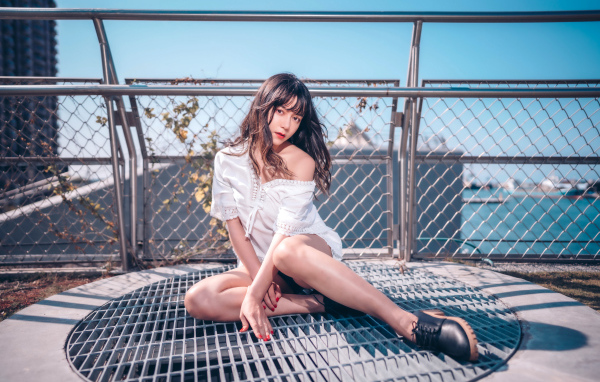 Девушка азиатка в белом наряде сидит на сетке