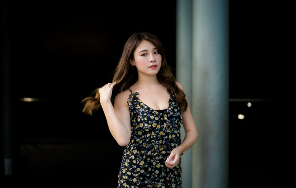 Девушка азиатка в платье трогает волосы 