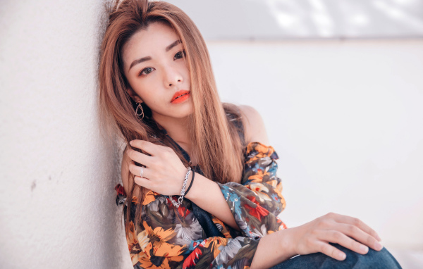 Девушка азиатка сидит на полу у стены 