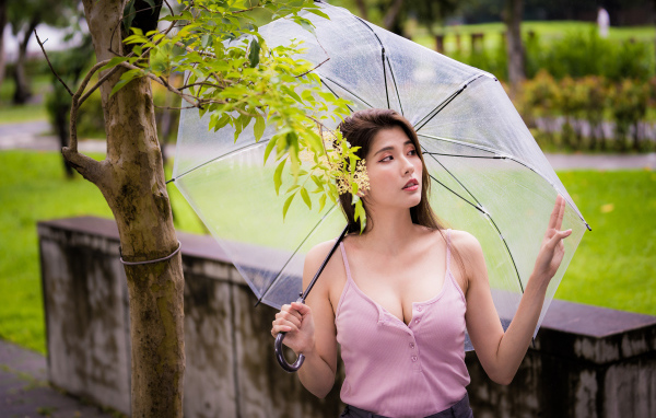 Девушка азиатка с прозрачным зонтом в парке