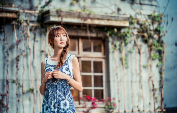 Красивая девушка азиатка в сарафане у старого дома 