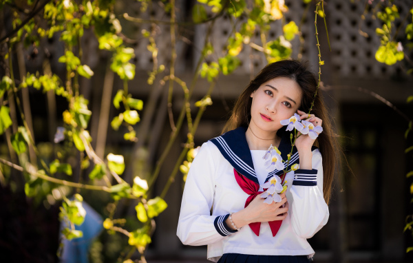 Красивая девушка азиатка в форме с цветами в руках 