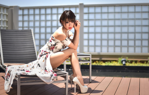 Красивая девушка азиатка сидит на шезлонге 