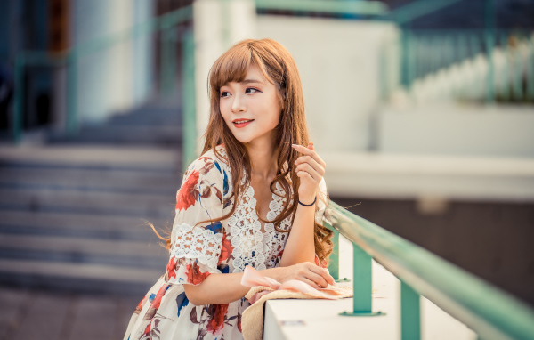 Красивая девушка азиатка стоит у перил 