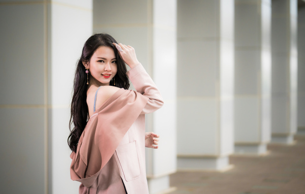 Красивая девушка азиатка с длинными волосами в розовом пальто 