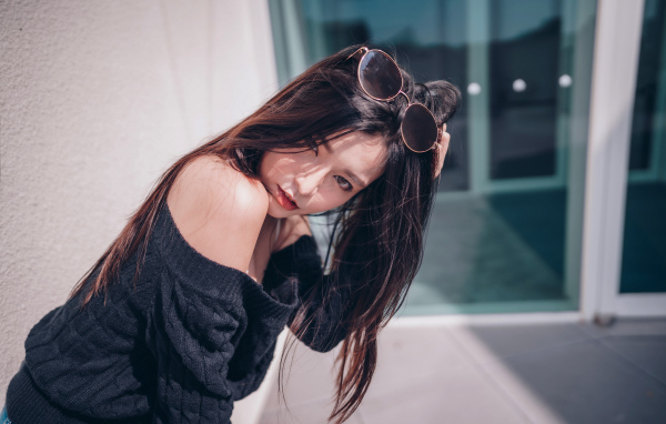 Красивая азиатка в черном свитере с солнечными очками на голове 