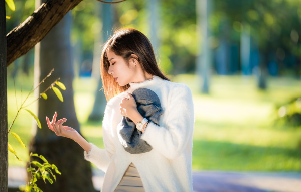 Красивая азиатка в белой кофте в солнечном парке