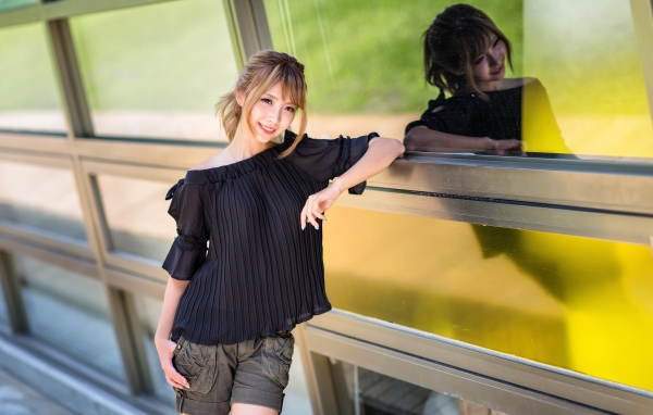 Красивая девушка азиатка в черной блузке у окна