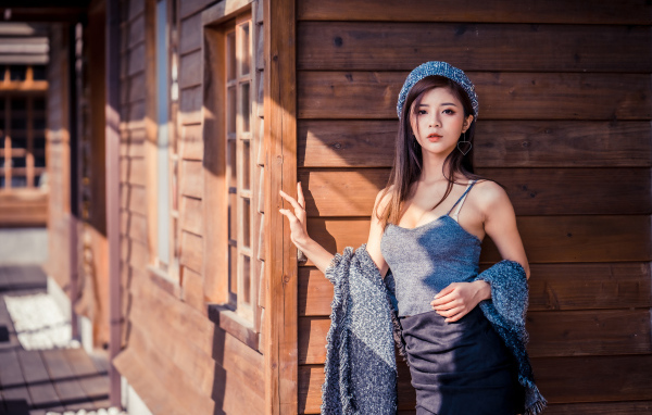 Красивая девушка азиатка стоит у деревянной стены 